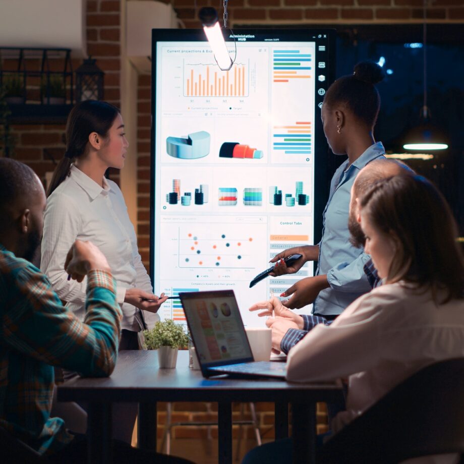 Diverse coworkers presenting analytics report, pointing at data visualization