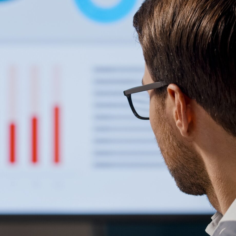 Young businessman working with financial analytics using TV multimedia in the evening