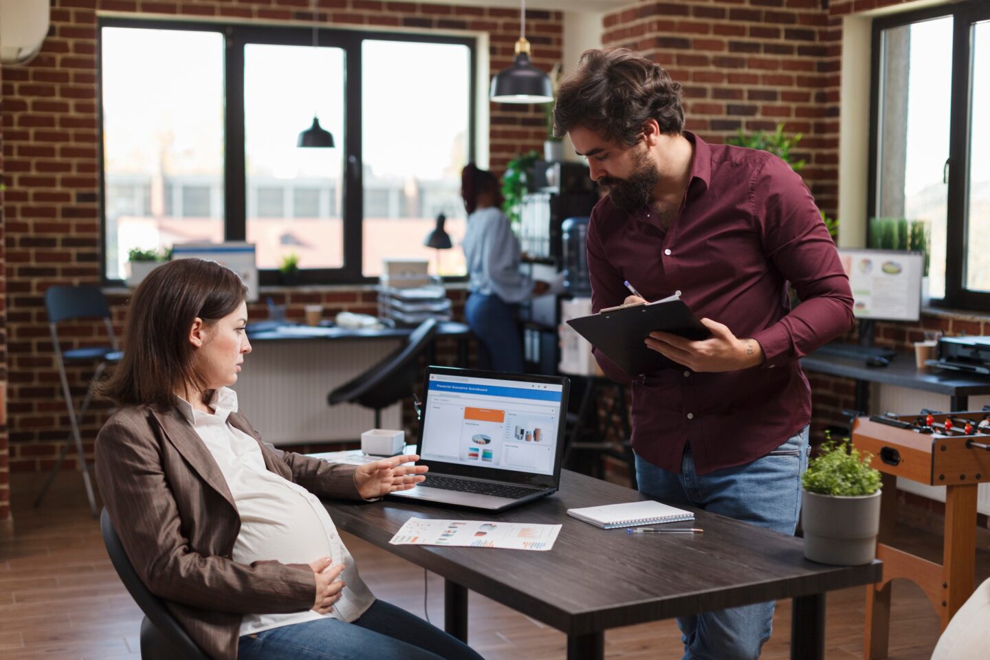 Pregnant project manager reviewing data charts and marketing analytics on laptop