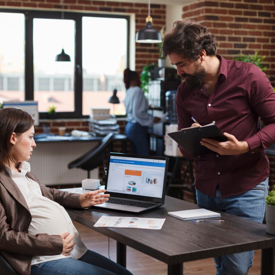 Pregnant project manager reviewing data charts and marketing analytics on laptop