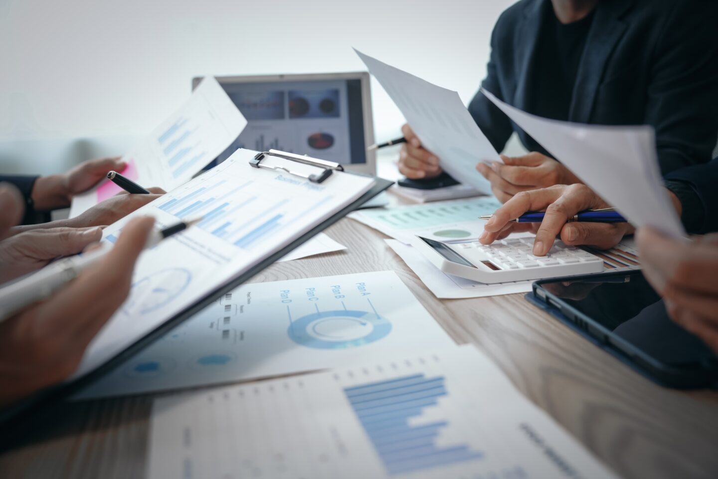 Professional business team meeting in formal suits, working at desks with financial papers