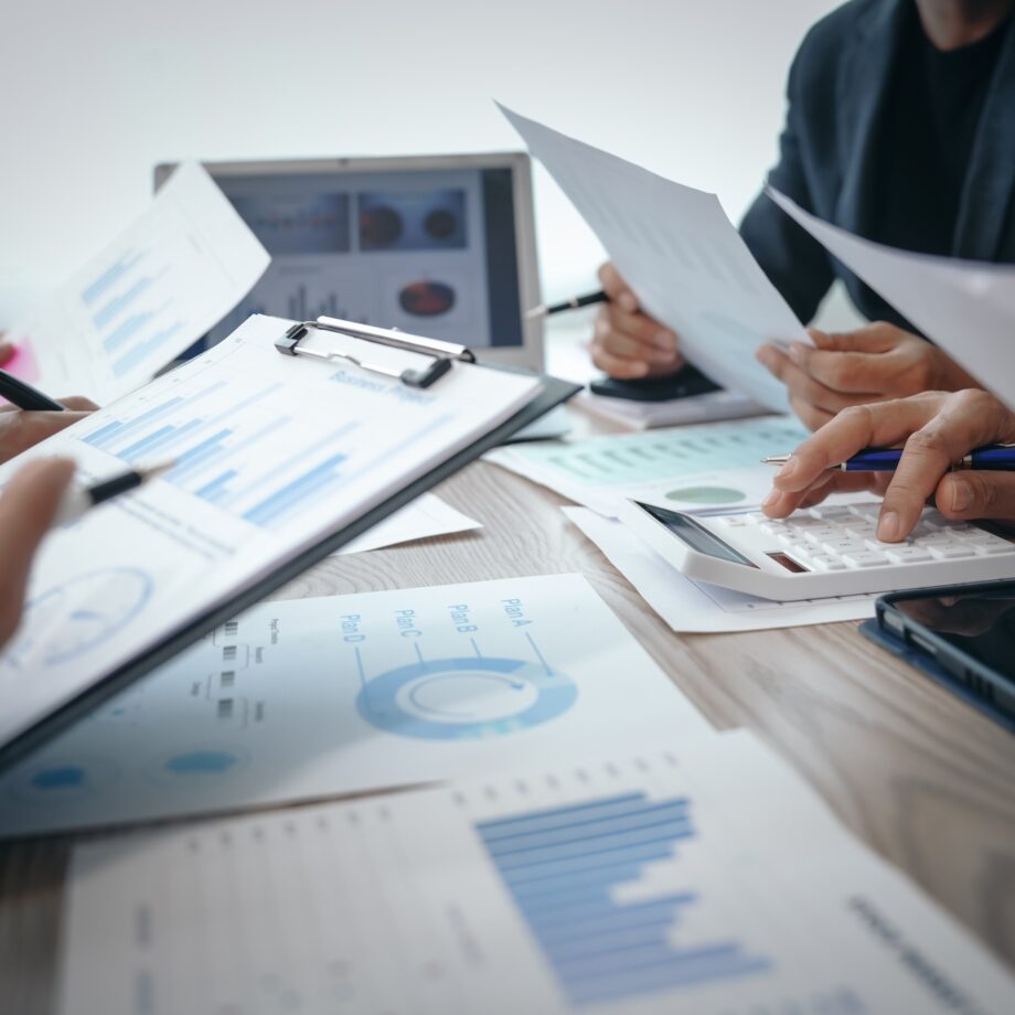 Professional business team meeting in formal suits, working at desks with financial papers