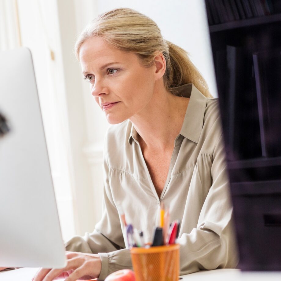 Female designer typing at desktop computer in creative studio