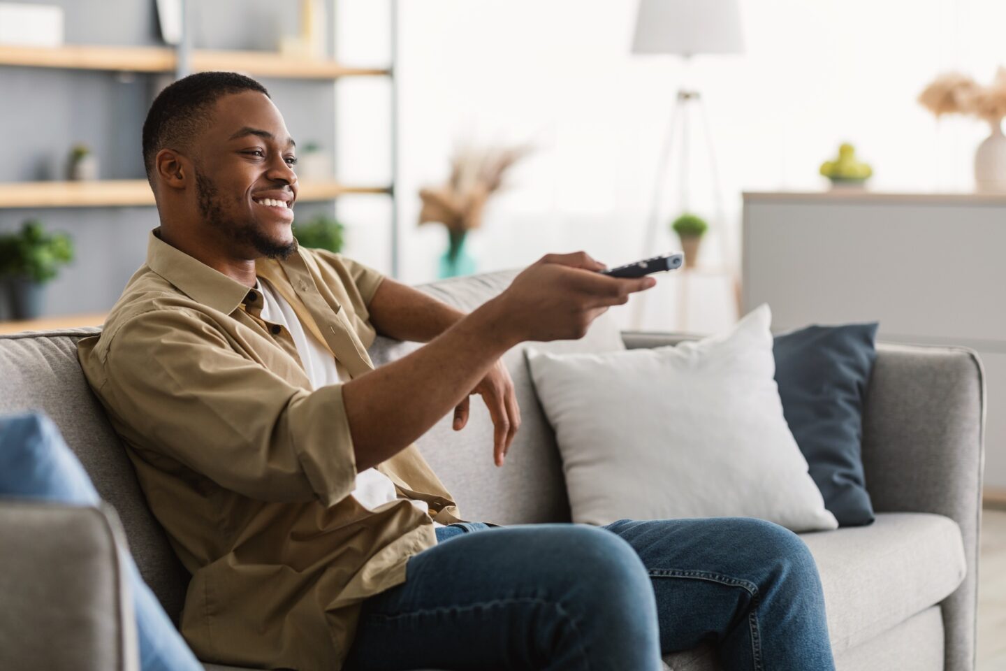 Happy African American Man Watching TV Switching Channels At Home