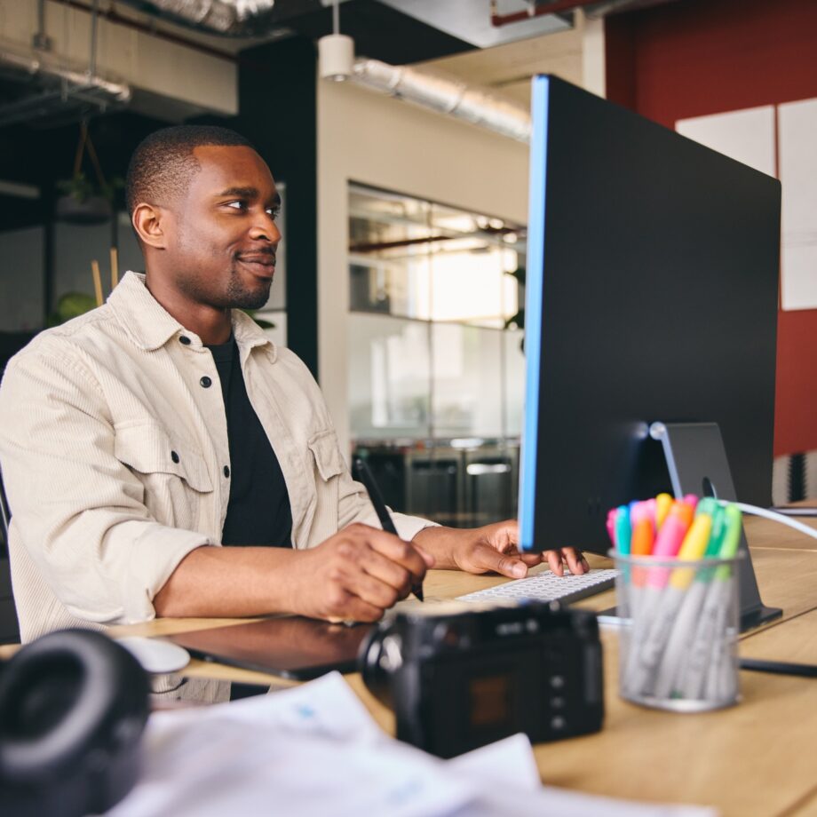Young Black Male Advertising Marketing Or Design Creative In Office Sitting At Desk
